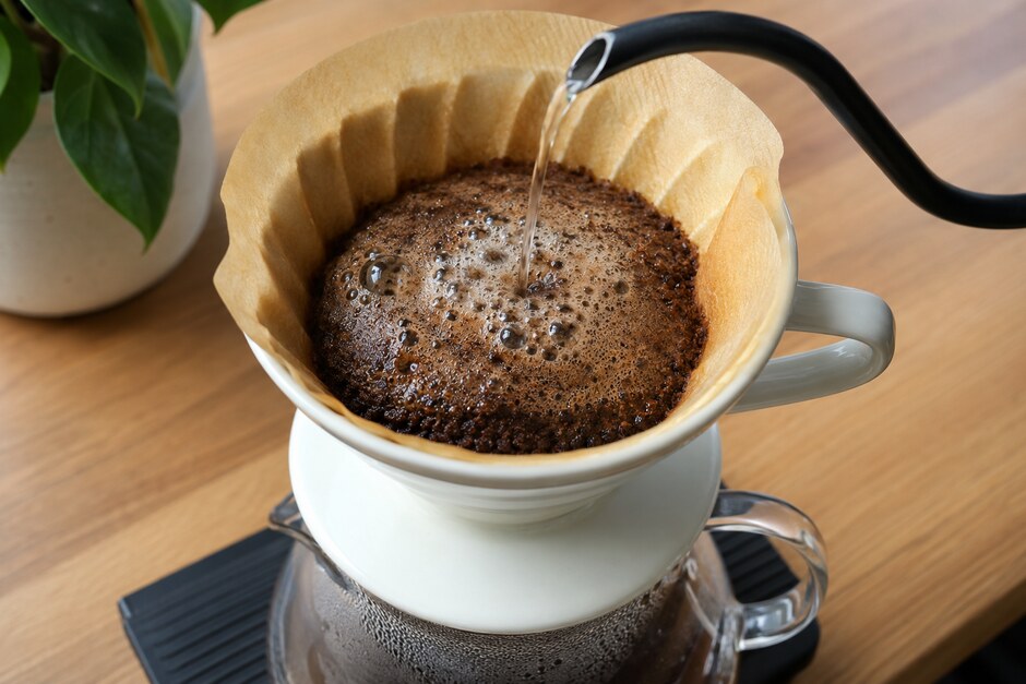 Fresh coffee blooming in a paper filter under a controlled stream from a gooseneck kettle.